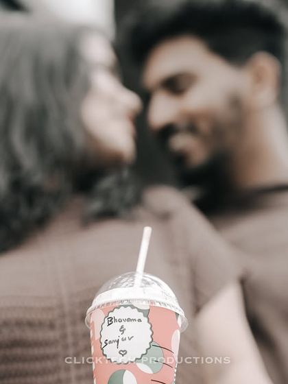 A creative close-up focusing on a personalized coffee cup, with the romantic couple blurred in the background.