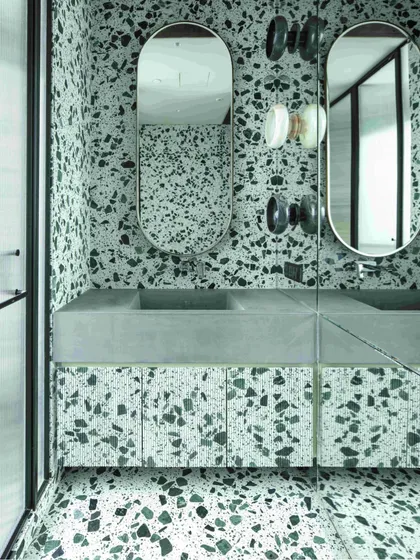 The younger daughter's bathroom in our Kolkata project, fully clad in a vibrant green and white terrazzo. The space features a custom concrete wash basin and fluted terrazzo shutters.