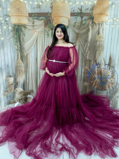 A full-length portrait of a mom-to-be in a beautiful magenta gown, taken in our boho studio.