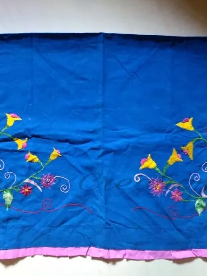 This is the full view of the embroidered blue fabric, showing how a corner pattern can be mirrored to create a balanced and beautiful design for a tablecloth or cushion cover.