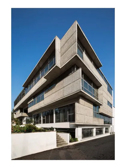This corporate office for a concrete equipment manufacturer uses patterned, form-finished concrete as its primary skin. The building's facade is a direct reflection of the client's products and technology, with deep, cantilevered planes that provide passive shading from the harsh western sun.
