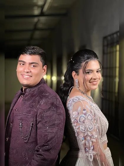 A fun back-to-back pose of the couple, showing off their stylish sangeet outfits.