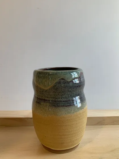A beautifully glazed vase with earthy tones of yellow and green dripping down the sides. A great example of glaze chemistry.