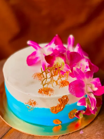 A simple two-tone cake in blue and white, made vibrant with fresh pink orchids and splashes of gold.