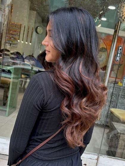 Inspired by a rich espresso, this hair transformation features a deep mocha base with lighter balayage pieces. The result is a sophisticated and warm color melt, styled into loose waves.