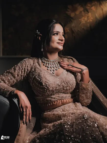 A classic seated portrait of Vanshika, using dramatic lighting to highlight the intricate details of her lehenga and diamond necklace.