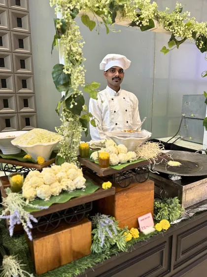 Our chef stands proudly at a live station for traditional Indian snacks. The setup is rustic and appealing, inviting guests to enjoy freshly made delicacies.