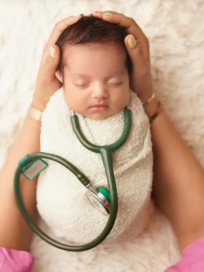 A future doctor in the making? This creative shot features a newborn swaddled with a stethoscope, held in their parent's hands. It's a beautiful way to honor a family's profession.