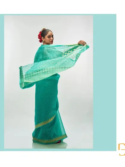 The light sea green saree in a dynamic pose, showing the beautiful movement and the geometric play of the gold zari checks.