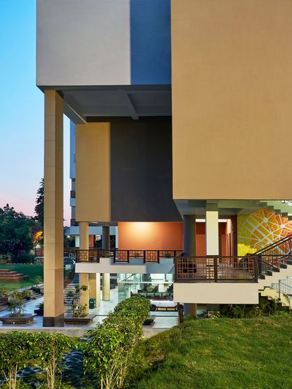 The architecture of the Sushant School rises from a landscaped base, where green courts and shaded stilted zones act as active cooling devices. This use of landscape for natural evaporative cooling helps maintain comfortable temperatures without air conditioning, even in extreme heat.