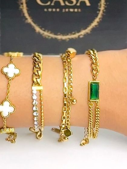 A detailed wrist shot displaying a variety of chain and charm bracelets against the product's packaging. This helps customers see the scale and detail of each piece up close.