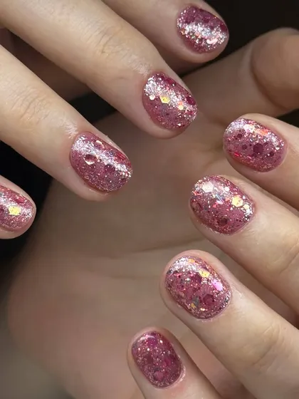 A playful and sparkly pink glitter manicure. This design features a mix of fine and chunky glitter particles for a multi-dimensional, festive look.