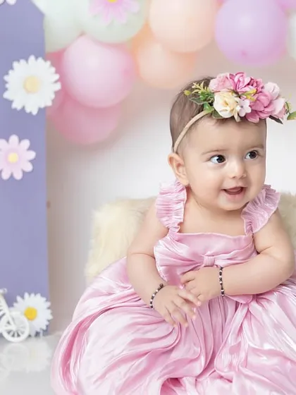 A joyful smile from this six-month-old princess, surrounded by a beautiful arch of pastel balloons and daisies.