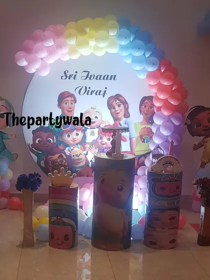 A Cocomelon party with a large character backdrop and themed pedestals. The pastel balloon arch adds a soft and pretty touch.