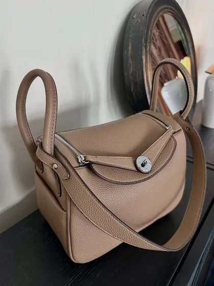 A detailed shot of the Linde Large bag, showing its smooth, structured shape and the quality of the taupe leather. The side profile highlights its spacious interior.
