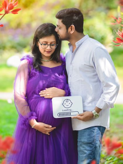 A cute and playful couple's shot in the park, using a "baby loading" sign to announce their joy.