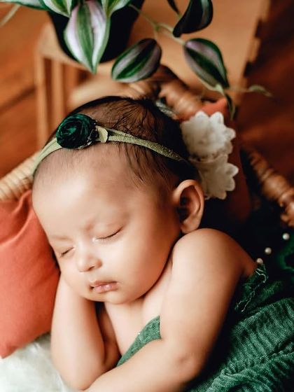 A close-up shot of a baby sleeping in a wicker basket. The small pillow and soft blanket ensure the baby is comfortable while adding to the rustic aesthetic.