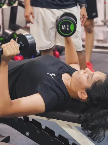 A player performs a dumbbell bench press, strengthening her chest, shoulders, and triceps for more powerful overhead shots.