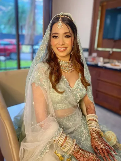 A happy bride Aashna in her unique mint-colored lehenga. The makeup is soft and luminous, with a sparkle in her eyes.