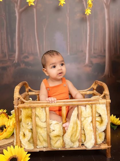 A sweet moment in our enchanted forest setup. This baby is sitting in a rustic wicker crib, surrounded by sunflowers and a woodland backdrop, creating a magical scene.