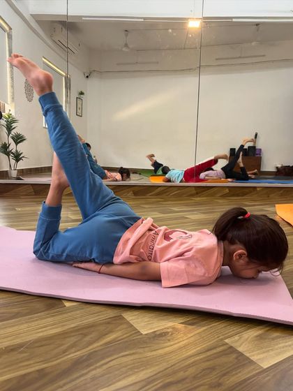 This young yogi is practicing a variation of Shalabhasana, or locust pose, which is great for strengthening the back muscles. I am always impressed by their strength.