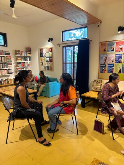 Two attendees deep in conversation in our cozy library space during a community event. The atmosphere at Koota is designed to encourage spontaneous connections.