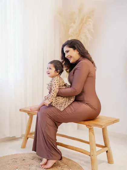 A sweet mother-daughter moment during a first birthday photoshoot. The simple wooden bench and soft lighting keep the focus on their loving interaction.