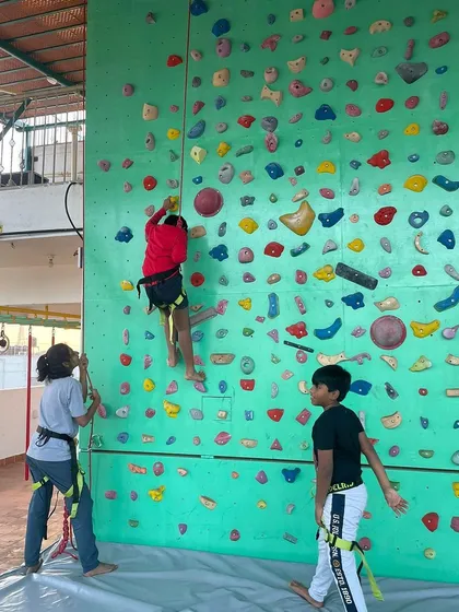 Safety is central to everything we do. This image shows our top-rope setup, where young climbers are securely harnessed and supported by a belayer on the ground, allowing them to climb higher with complete confidence.
