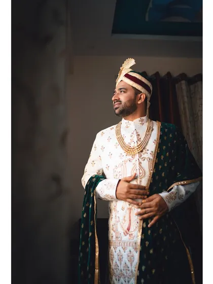 A classic portrait of the groom on his wedding day. Dressed in a white and gold sherwani with a velvet shawl, he looks regal and ready for the big moment.