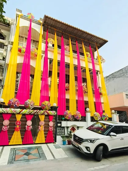 Wedding celebrations often start at home, and I ensure they are just as beautiful. Here's a full home exterior I decorated with bright pink and yellow drapes and traditional elements for a festive feel.
