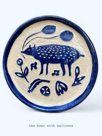 'The Boar with Balloons' is a whimsical, hand-painted plate that tells a little story. I enjoy creating these narrative pieces that blend folk art style with a touch of modern humor.