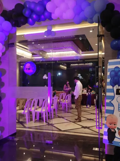 The entrance to the Boss Baby party, with a blue, black, and white balloon arch and a custom welcome board.