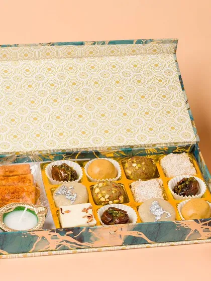 An open box of assorted Indian sweets, styled for a Diwali catalogue. We arrange each sweet carefully to showcase the variety and craftsmanship.
