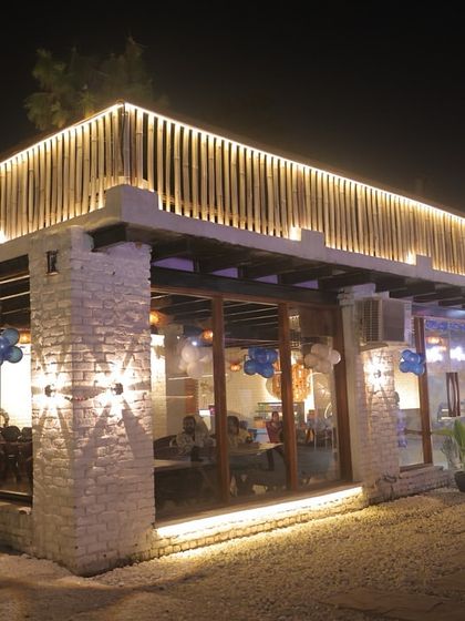 The exterior of Sasa Cafe lit up at night. The warm lights along the roofline and inside create a welcoming glow, inviting you into the cozy space.