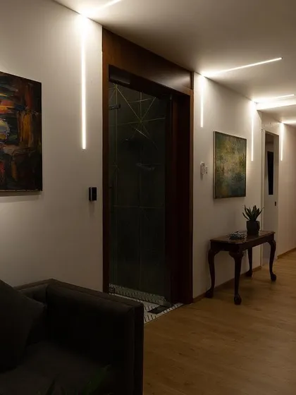 In this view of the corridor, the linear lights create a clean, architectural look. The lighting is designed to make the transitional space feel inviting while effectively illuminating the art, turning the hallway into a small gallery.
