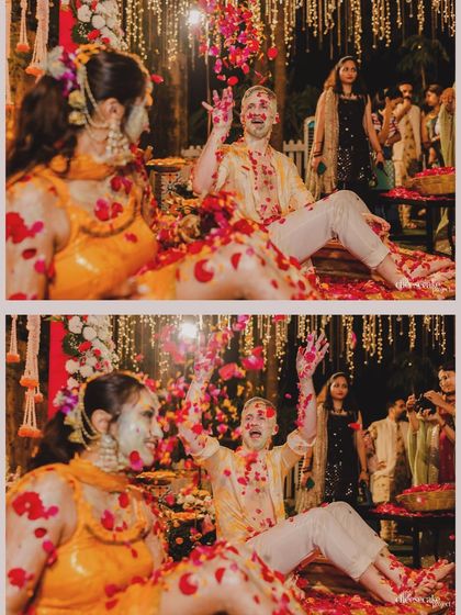The groom throws his hands up in a shower of flower petals, a moment of pure celebration during the Haldi.