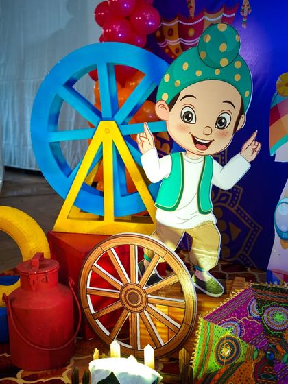 A cute cartoon prop of a boy in a turban, standing next to colorful wheels and a milk can.