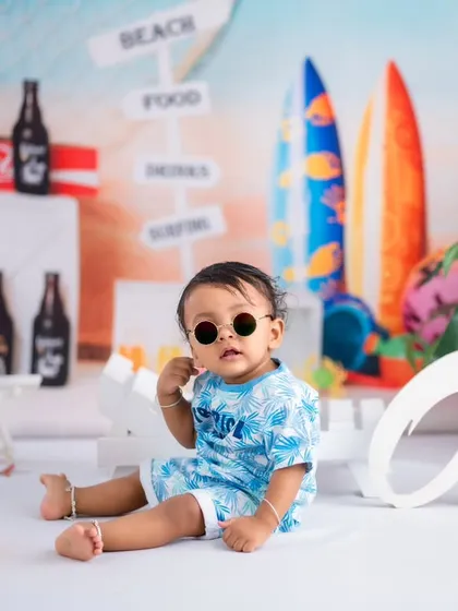 A toddler striking a cool pose with round sunglasses in our beach setup. We encourage kids to be themselves, which results in photos full of personality.
