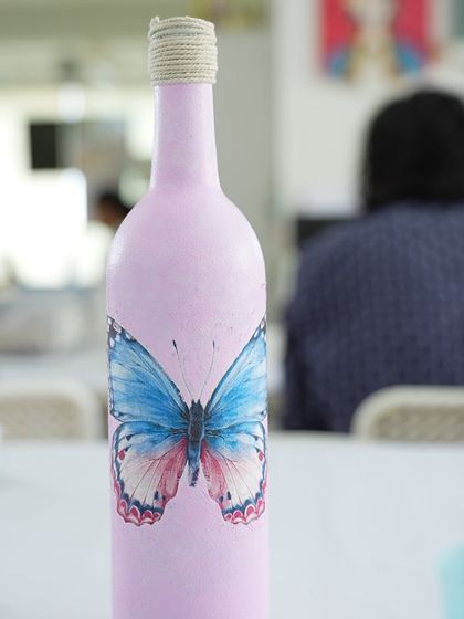A close-up of a beautifully decorated decoupage bottle with a butterfly design. This workshop is all about creating delicate and charming pieces.