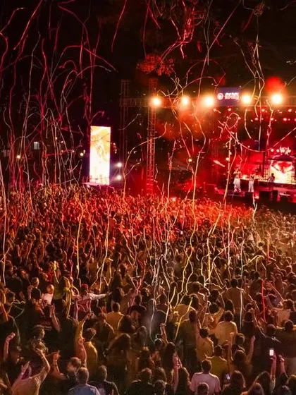 Confetti rains down on a massive audience, celebrating the peak of a live hip-hop festival performance.