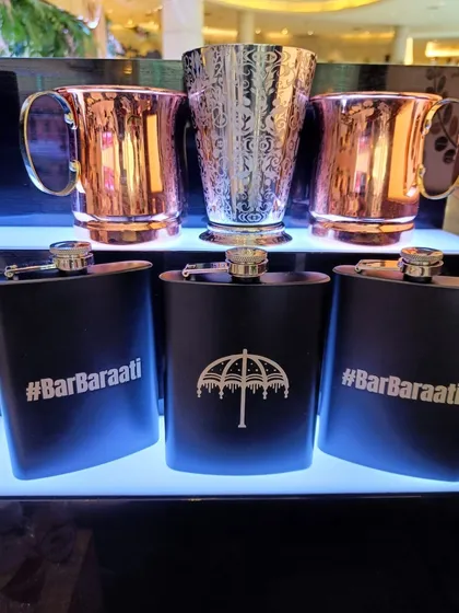 I can create custom merchandise and party favors for your guests. This display shows personalized hip flasks alongside elegant copper and silver mugs, making for a stylish and memorable wedding giveaway.