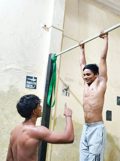 A coach giving pointers to a student on the bar. This personalized feedback is what helps our members improve so quickly.