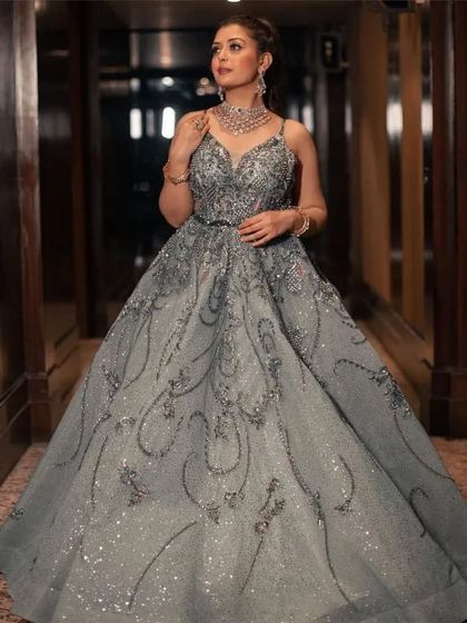 A client posing in a hotel corridor in a sparkling grey ball gown with intricate silver patterns. This dress is pure elegance.