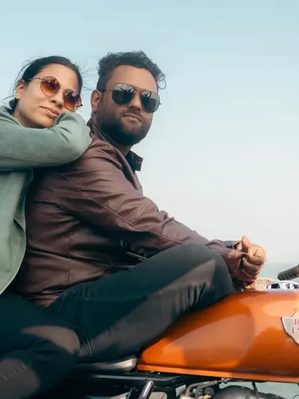 A relaxed and loving pose on their motorcycle. She leans against him, both looking cool and confident, with the open water behind them. This is a perfect shot for a save-the-date.