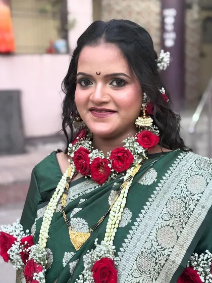 A close-up of the mom-to-be, looking radiant in her green saree and floral jewelry. The makeup is kept fresh and celebratory.