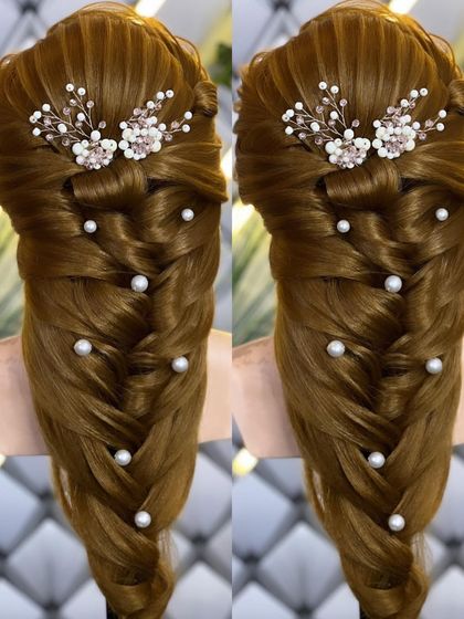 A detailed look at a mermaid braid on a mannequin, adorned with pearls and a floral hairpiece.