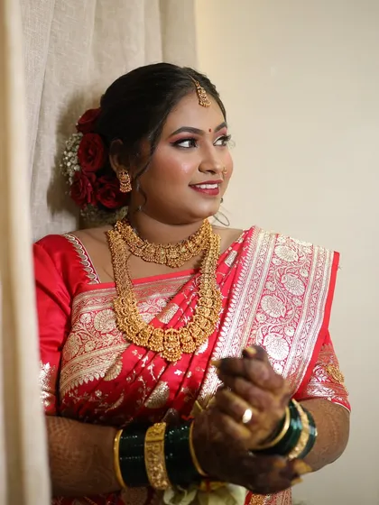 A candid moment of a bride in a stunning red saree, her makeup looking flawless and radiant.