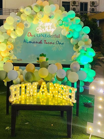 The birthday setup at night, with green lighting on the balloons creating a unique and vibrant party atmosphere.