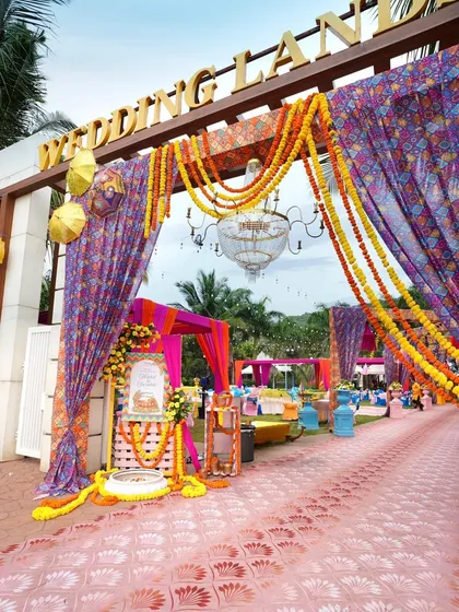 The entrance to the celebration sets the tone for the entire event. For this Mehendi, we combined traditional marigold garlands with colorful printed drapes and a grand chandelier to create a festive and welcoming vibe from the very first step.