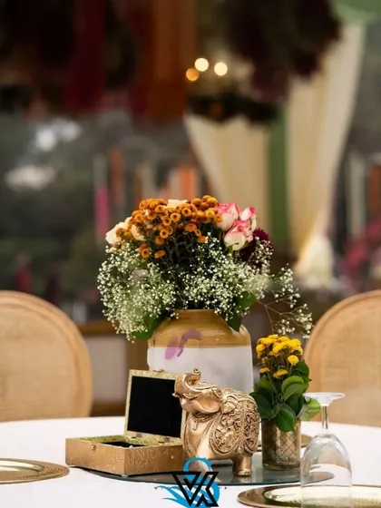A beautifully styled tabletop featuring a floral arrangement, a decorative golden elephant, and other small props. These curated details add personality and charm to guest tables.